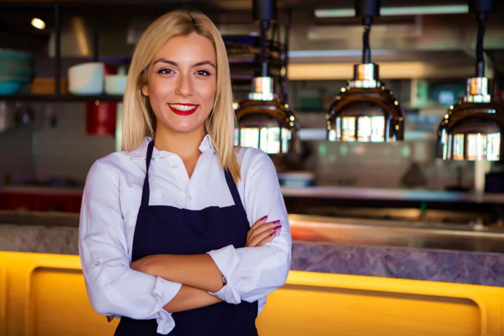 Fine dining waitress posing in front of kitchen