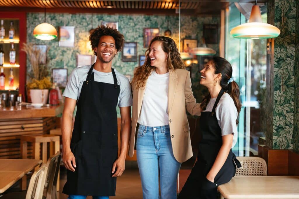 Happy restaurant manager with two employees.