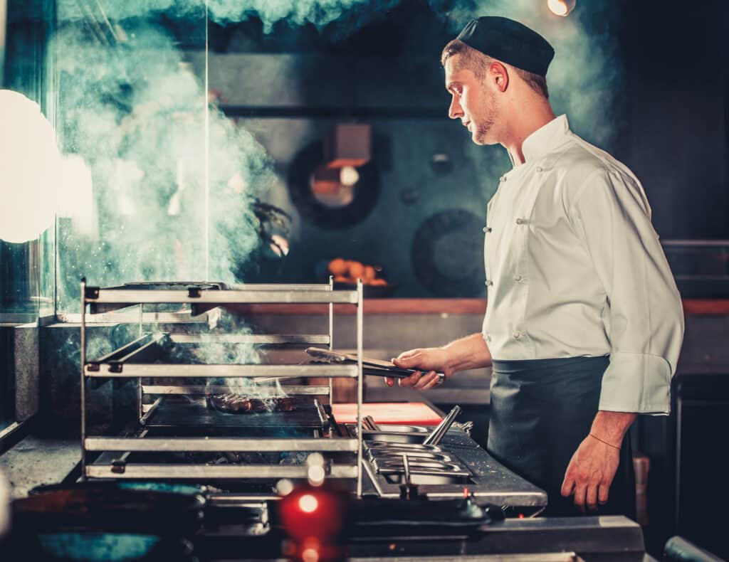 Cook preparing meal on the grill in kitchen